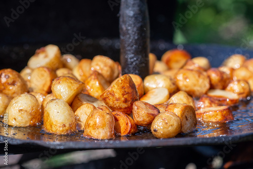 Grilled potato on frying pan on open fire