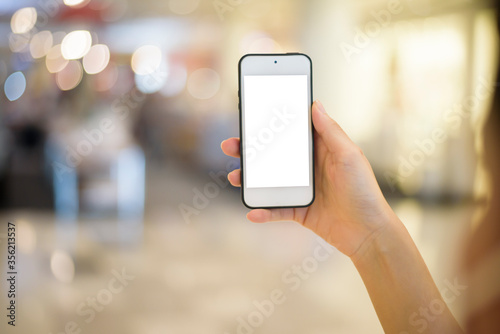 woman hand is holding cell phone mockup on shopping center background