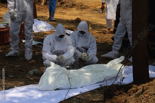 Relative who wearing personal protection kit mourn next of a man who died form the coronavirus disease COVID-19 before lowering his  body into a graveyard at the burial designated spot for COVID-19 at