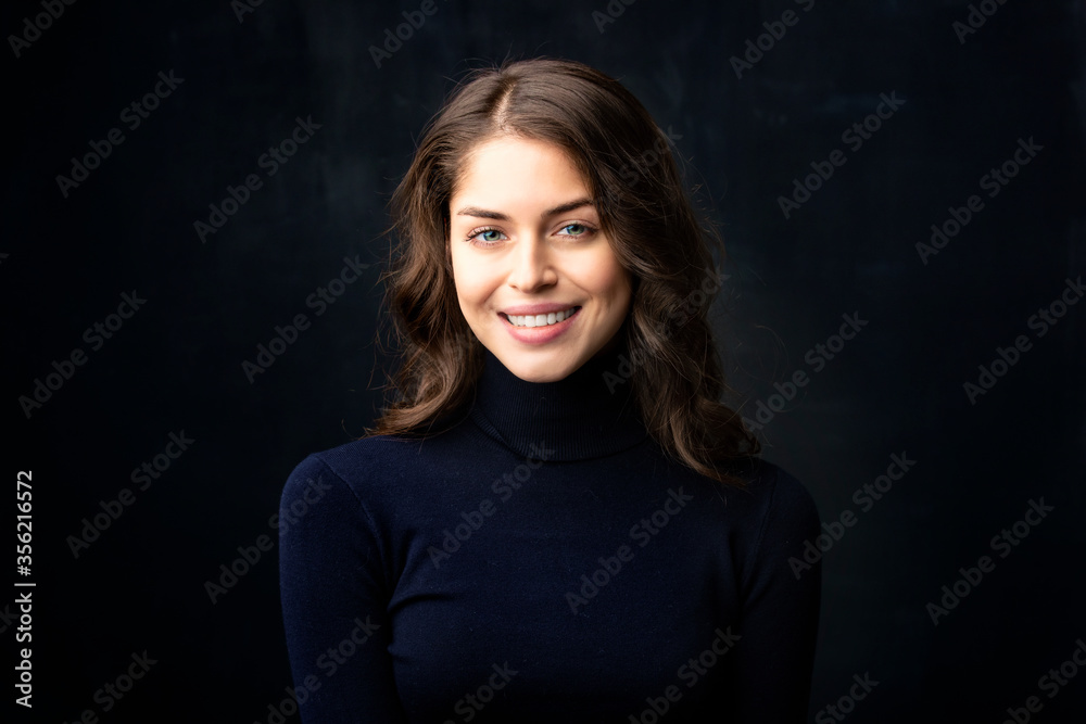 Attractive young woman close-up studio portrait at isolated dark background