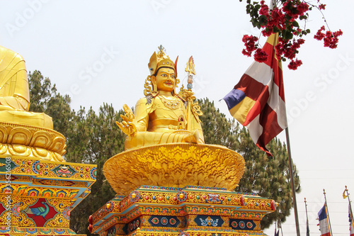 Large gold colored Guru Rinpoche (also known as Padmasambhava) statue in sunny day in Amideva Buddha Park located in the western part of Kathmandu city, Nepal. Religious architecture theme. photo