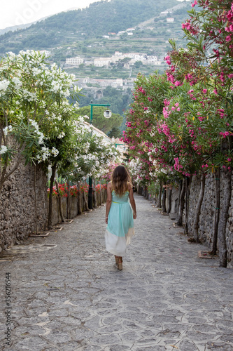 Italy old town pathway with flowers on each side and a woman walking
