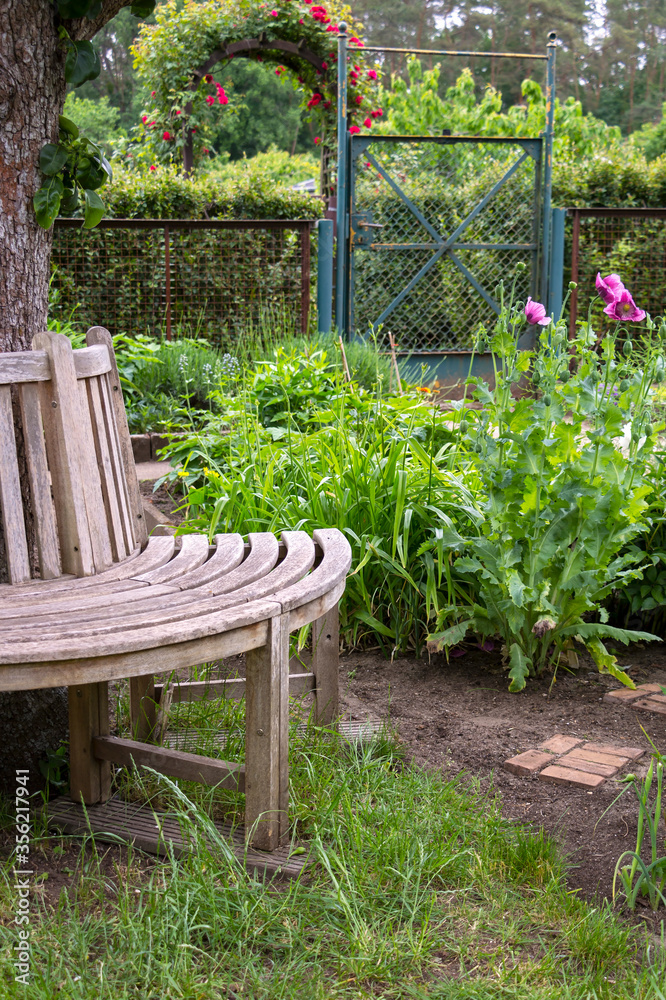 View of a wooden round bench in an allotment garden.