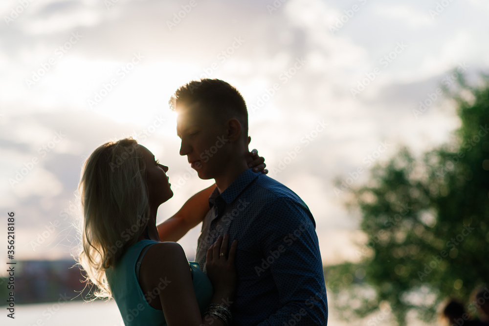 Couple in love back light silhouette at lake orange sunset Couple in love back light silhouette at lake orange sunset