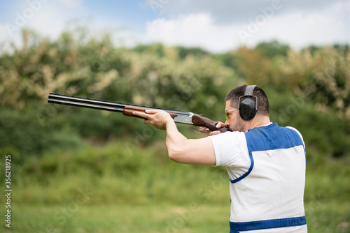 Man shooting skeet with a shotgun.