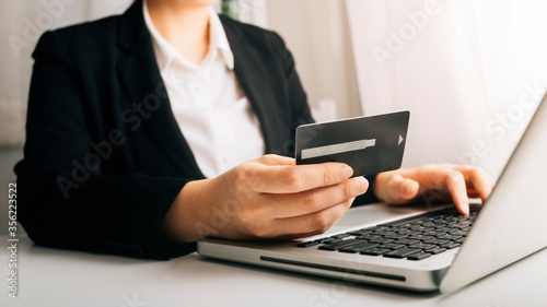 businesswoman hand using smart phone,tablet payments and holding credit card online shopping,omni channel,digital tablet docking keyboard computer at office in sun light