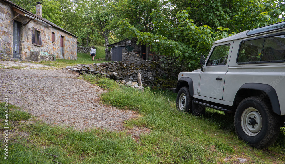 mountain trail with a parked beige All-terrain car and a person walking. mountain trail with a parked beige All-terrain car and a person walking.