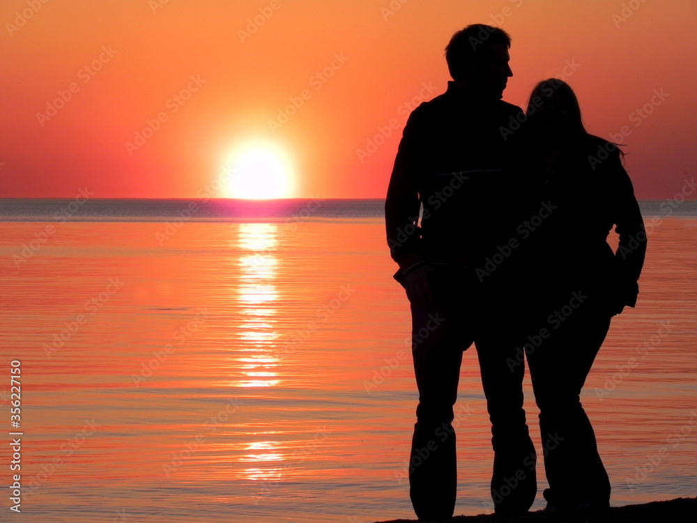 young couple watching sunset on the beach