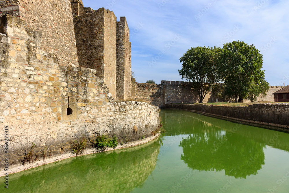 Amazing ancient Smederevo fortress stone walls with towers and reflection in moat or channel with green water