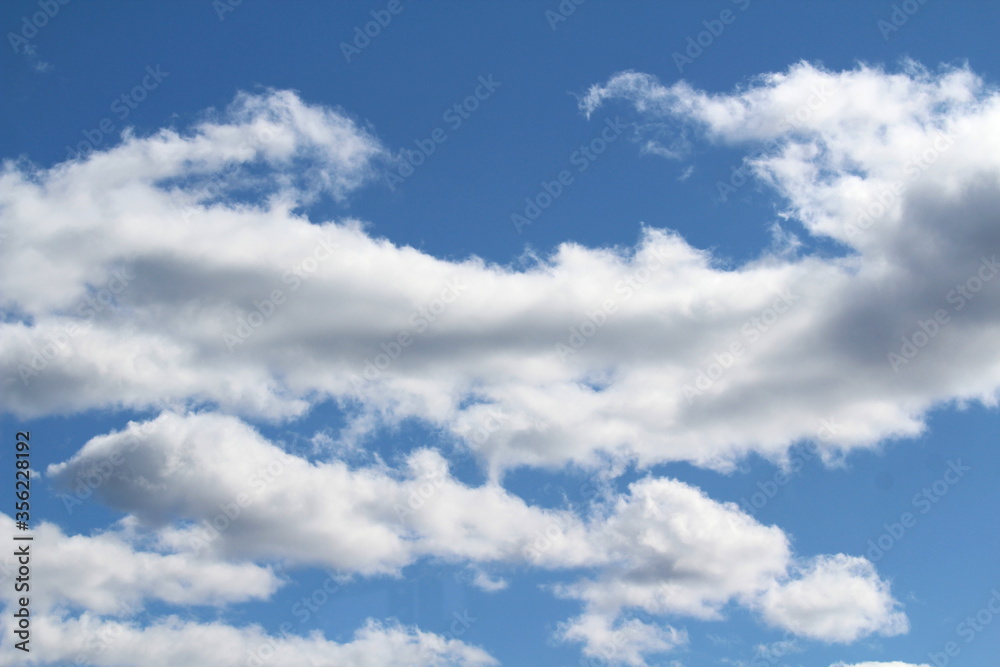 White fluffy clouds on a background of blue sky in summer. The concept of weather and climate White fluffy clouds on a background of blue sky in summer. The concept of weather and climate