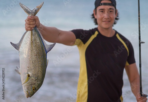 Proud fisherman holding a live saltwater fish from the ocean. photo