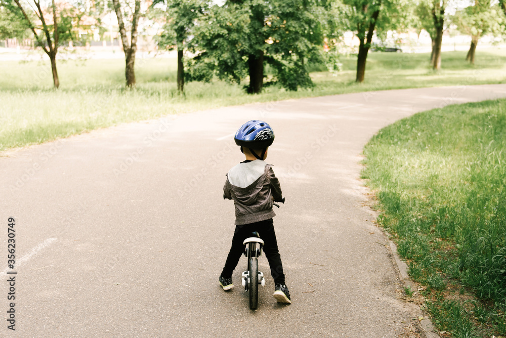 Happy little boy riding a bike running in the Park