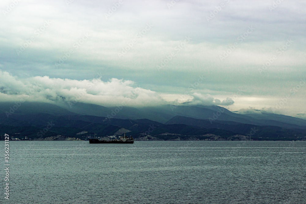 Clouds on mountain and ship on the raid near the port in bay near Novorossiysk.