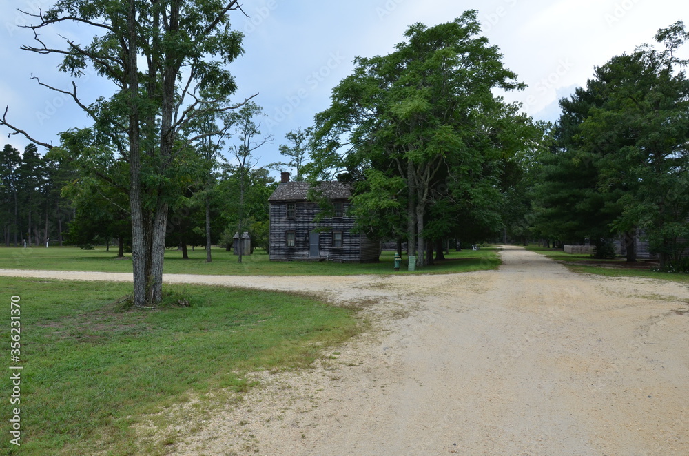 gravel road with wood houses and trees and grass