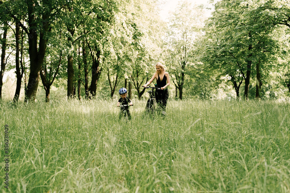 Happy little boy rides a bike with a young mom in the Park
