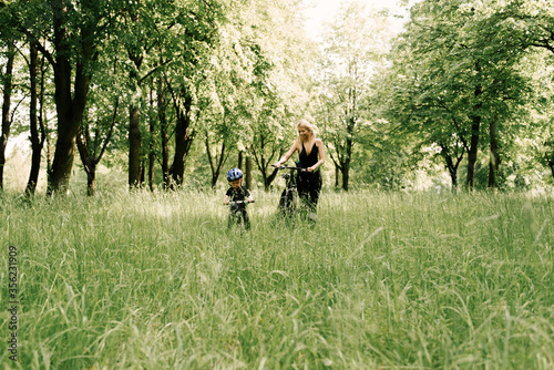 Happy little boy rides a bike with a young mom in the Park © ksyusha_yanovich