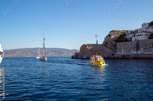 Water taxi moving at entrance of harbor of amazing greek island Hydra