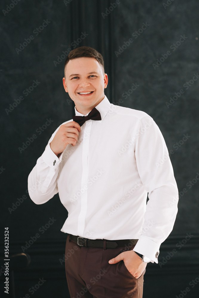 A young man of European appearance. Groom or man. Dressed in pants and a shirt and bow-tie. Portrait in a classic interior or studio. Entrepreneur or freelancer. close-up, face.