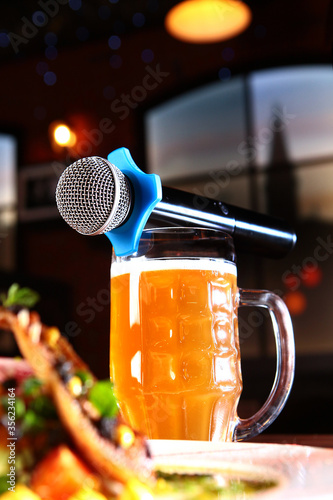 The karaoke microphone is on top of a beer mug.A plate of food on the table. The concept of a karaoke restaurant. Copy of the space.