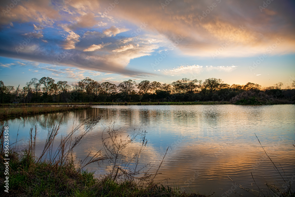 Colorful Clouds Reflected in Tranquil Waters of a Pond in South Central Louisiana at Sundown in Early Spring