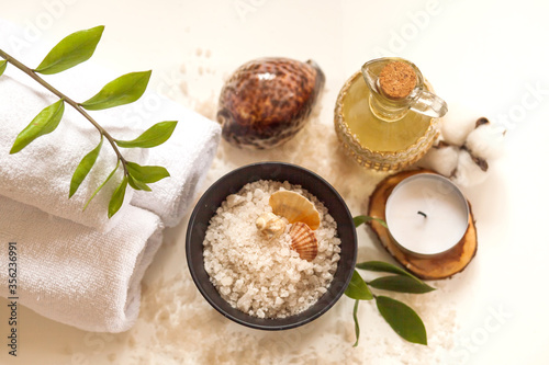 Spa, beauty and wellness. Towel, cosmetic massage oil, leaf, sea salt with shells and candle. Top view, flat lay on white backgroun