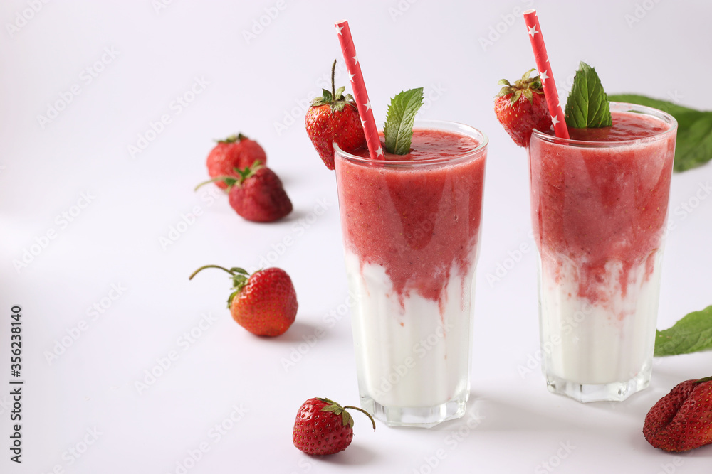Two servings of homemade smoothies with fresh strawberries, mint and yogurt in glasses on white background, Diet and weight loss control concept Two servings of homemade smoothies with fresh strawberries, mint and yogurt in glasses on white background, Diet and weight loss control concept