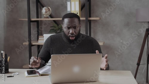 shocked millennial african american man in glasses looking at laptop screen. Frustrated guy worrying of bad surprise or problem or unbelievable news