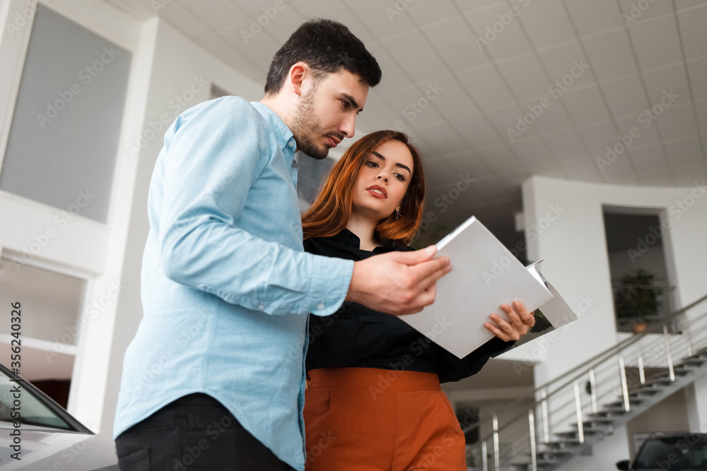 Couple looking at car dealership journal Couple looking at car dealership journal