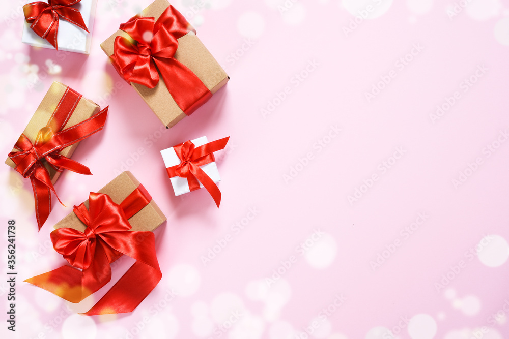 Beautiful composition with gifts with red ribbons on a pink background. Box with presents. Top view. Beautiful composition with gifts with red ribbons on a pink background. Box with presents. Top view.