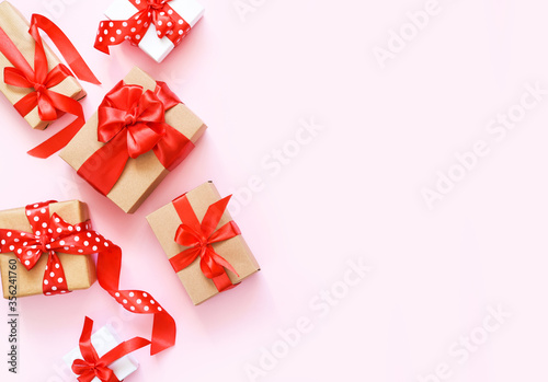 Beautiful composition with gifts with red ribbons on a pink background. Box with presents. Top view.