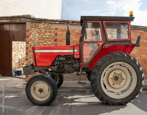 Red tractor parked in rural village.
