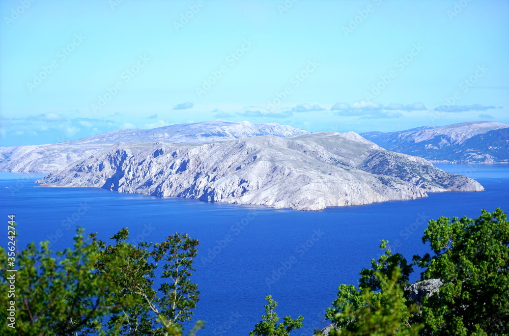 Aerial view of the rocky island in the blue sea and the turquoise sky lighted by the morning sun