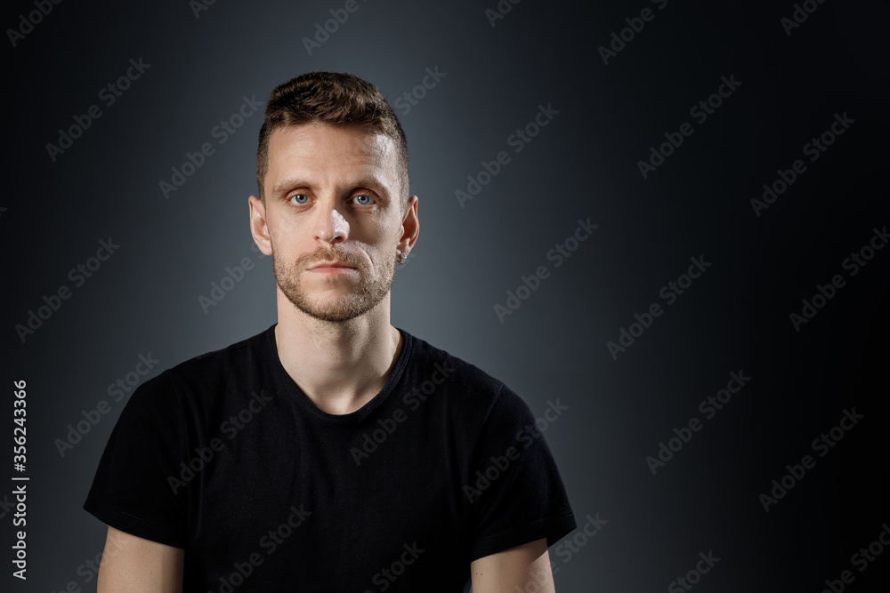 Young man, showing no emotions on black background.