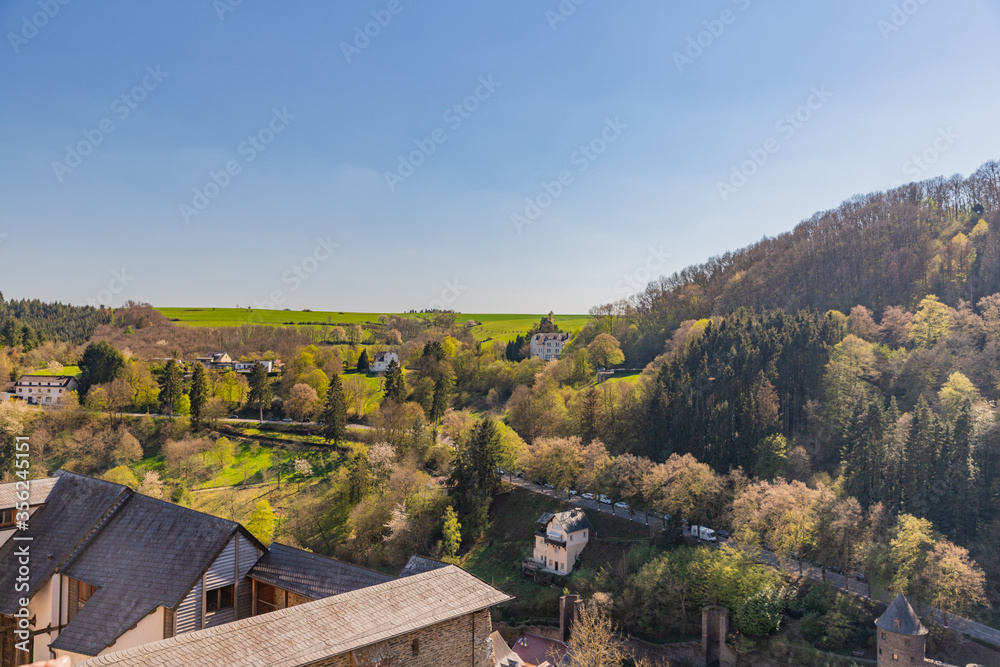 Obraz premium Village of Vianden with road between green fields view from castle, Luxembourg