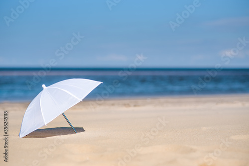 white umbrella on the beach against the sea