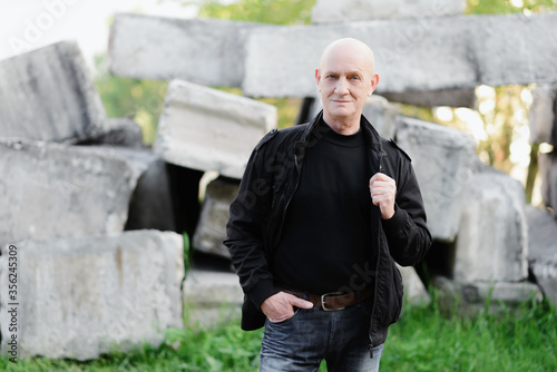 An elderly man stands on a background of concrete slabs. High quality photo