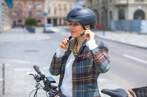 young woman putting bicycle helmet on street