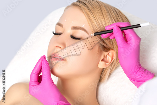 Woman Having Permanent Make-up Tattoo on her Eyebrows.Permanent make-up for eyebrows in beauty salon. Closeup beautician doing tattooing eyebrow. Professional makeup and cosmetology skin care.