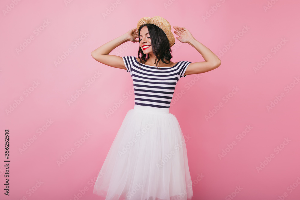 Jocund latin woman with black hair posing with eyes closed. Indoor portrait of pretty tanned girl enjoying photoshoot on pink background. Jocund latin woman with black hair posing with eyes closed. Indoor portrait of pretty tanned girl enjoying photoshoot on pink background.