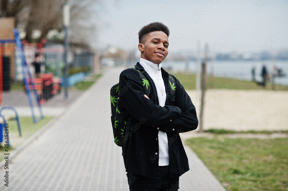 Young millennial african boy walking in city. Happy black man with marijuana backpack. Generation Z concept.