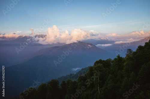 Beautiful natural background with Caucasus mountains. Pink clouds on the sunset, summer season