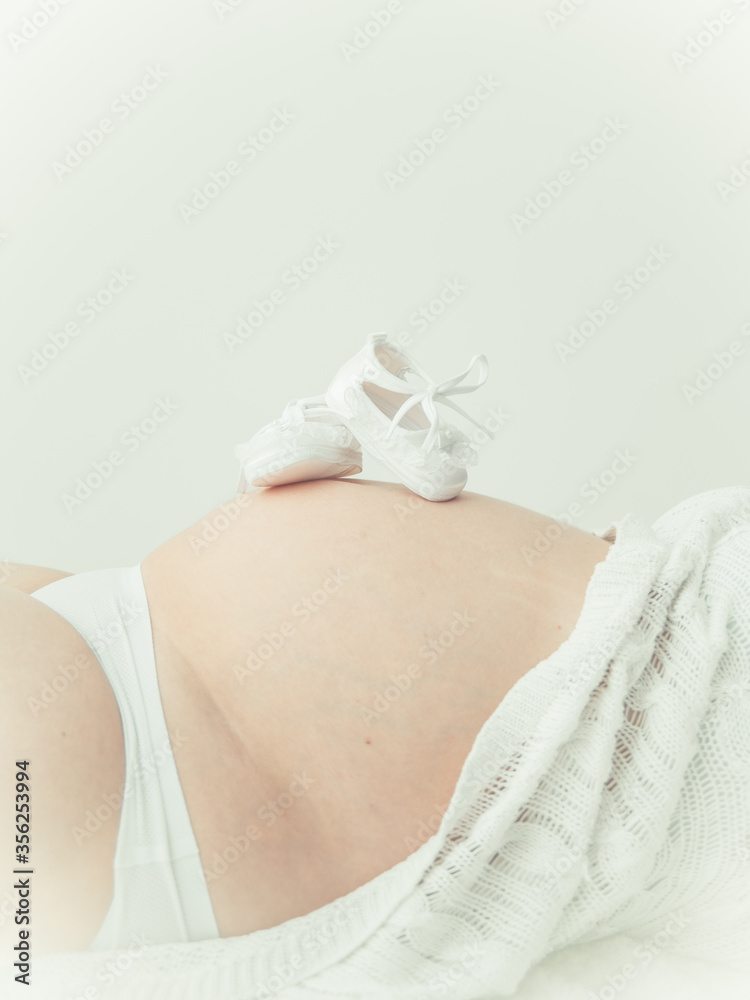 Fototapeta premium pregnant woman holding baby shoes