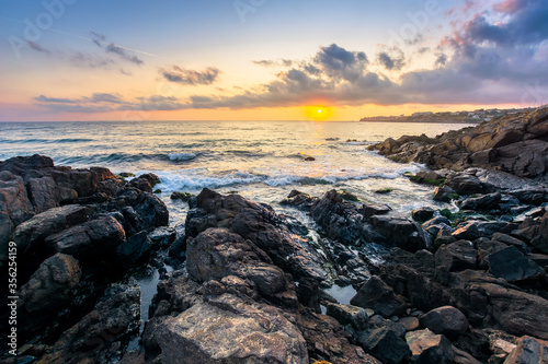 beach of the sea at sunset. wonderful scenery with stones in the water. beautiful clouds above the sun and horizon. concept of zen mood and spirituality