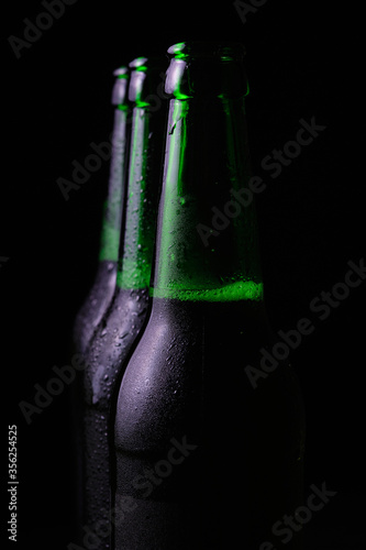 Three misted open bottles of cold beer on a black background.