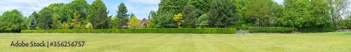 Foto Panoramic view of farm house with large green hedge to foreground