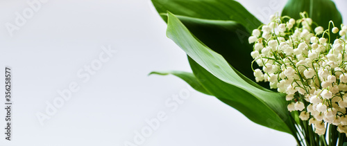 bouquet of lilies of the valley on a gray background, wide format with place for text. natural background