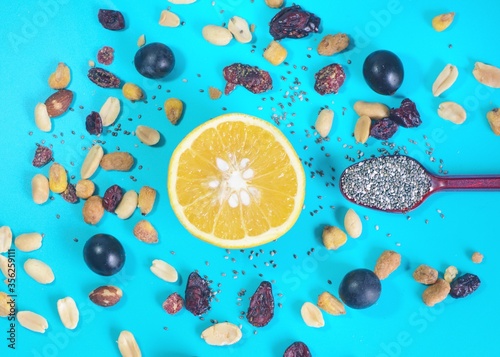 Vista aérea de varias frutas y semillas en una mesa azul. Vista aérea de media naranja rodeada de uvas, frutos secos, nueces y una cucharita con chía. Comida saludable. photo