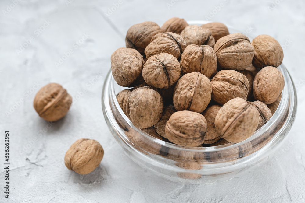 Uncracked walnuts in shell in bowl on gray background, concept of healthy eating vegan food. Close up, selective focus, copy space Uncracked walnuts in shell in bowl on gray background, concept of healthy eating vegan food. Close up, selective focus, copy space
