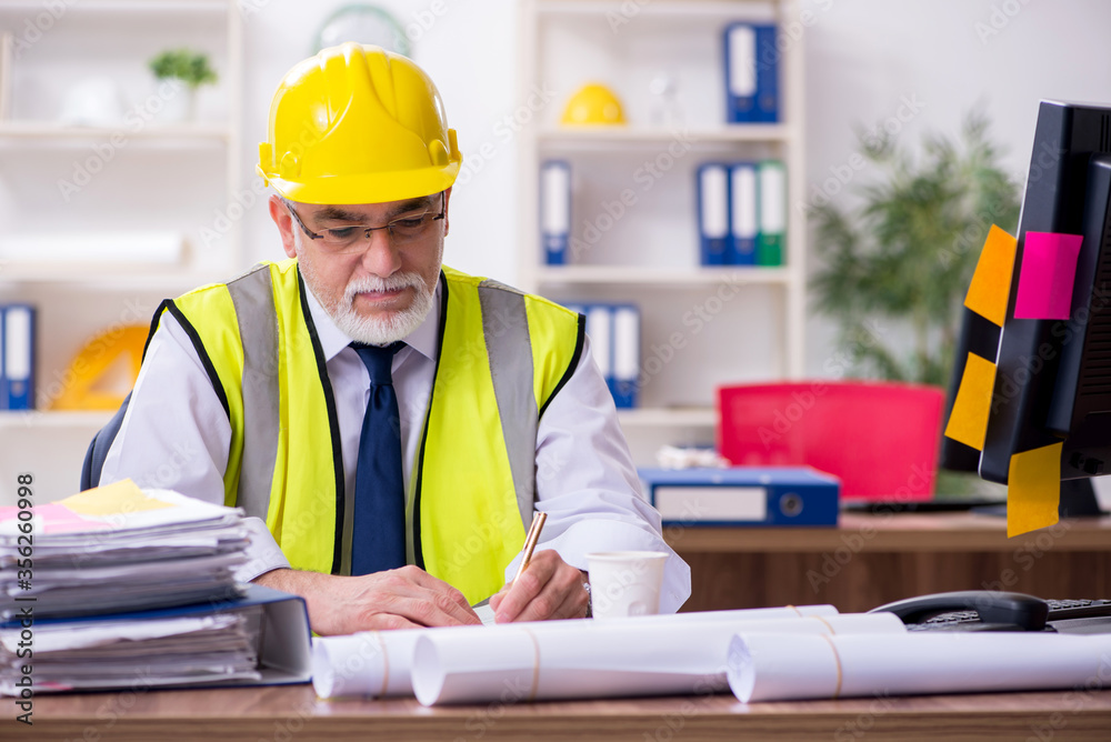 Old male architect working in the office Old male architect working in the office
