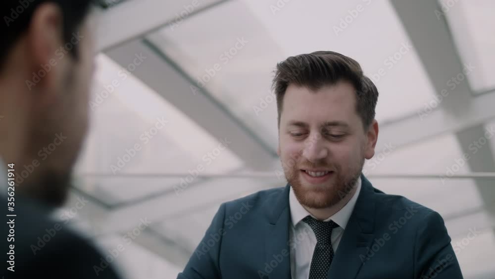 Man in suit looking happy while sitting behind desk Man in suit looking happy while sitting behind desk